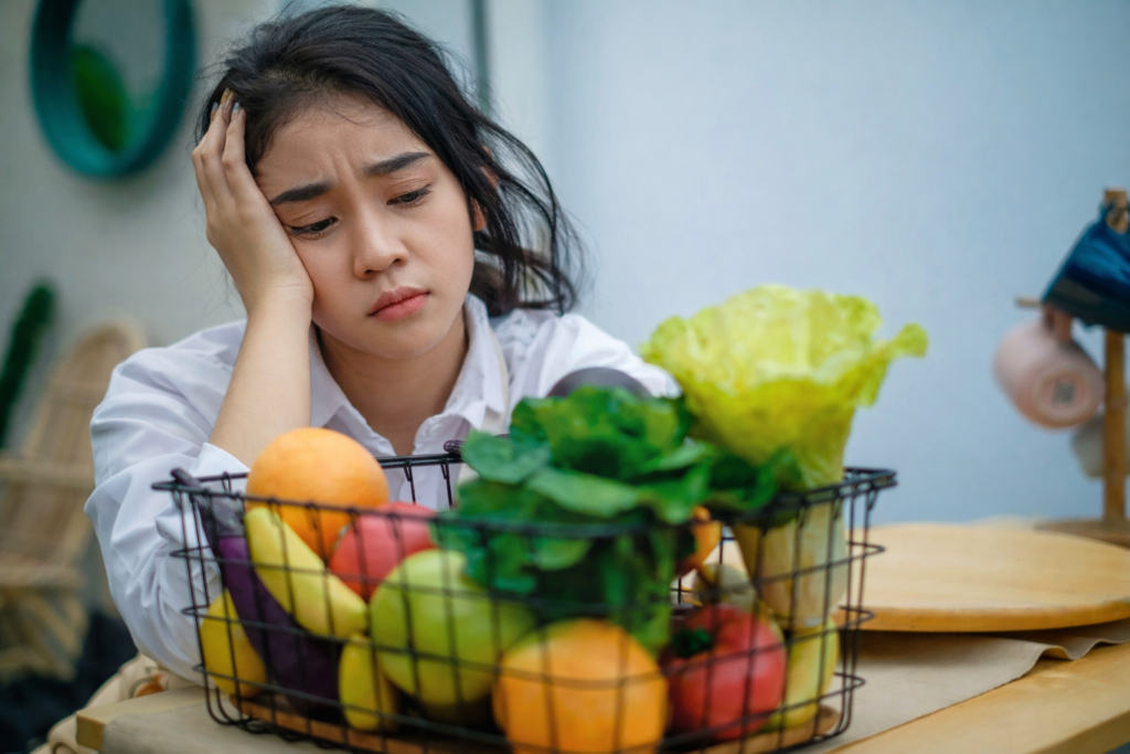 Femme fatiguée et perdue face à une alimentation saine malgré des symptômes persistants et une digestion difficile